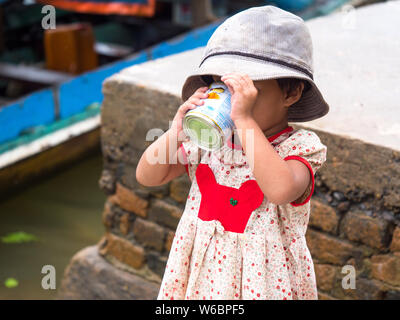 Tagu, Myanmar - 8. November 2017: Kleine Mädchen trinken, gesüßte Kondensmilch in der kleinen Stadt Tagu in der tanintharyi Region des Südlichen Myanma Stockfoto