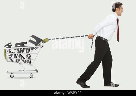 Mann schleppt Rupie-Symbole in einen Warenkorb Stockfoto