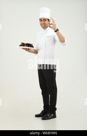 Der Koch hält einen Kuchen und zeigt das Schild OK Stockfoto