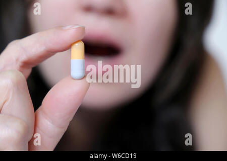 Frau nimmt eine Tablette, Kapsel in weiblicher Hand. Krankes Mädchen mit Medikamente, Schmerzmittel, Antibiotika oder Vitamin Stockfoto