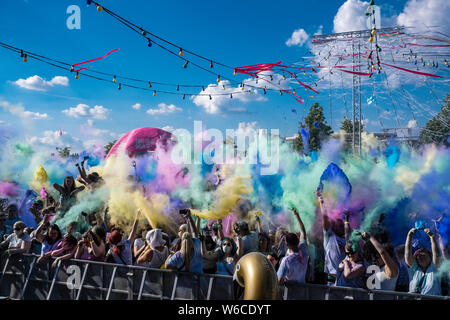 Hunderte von jungen Menschen feiern Holi, das Fest der Farben, werfen Farbe Pulver in der Luft Stockfoto