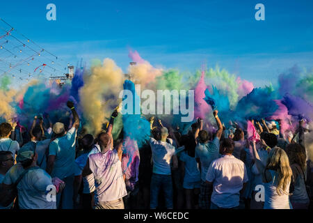 Hunderte von jungen Menschen feiern Holi, das Fest der Farben, werfen Farbe Pulver in der Luft Stockfoto