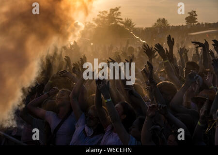 Hunderte von jungen Menschen feiern Holi, das Fest der Farben, bei Sonnenuntergang Stockfoto