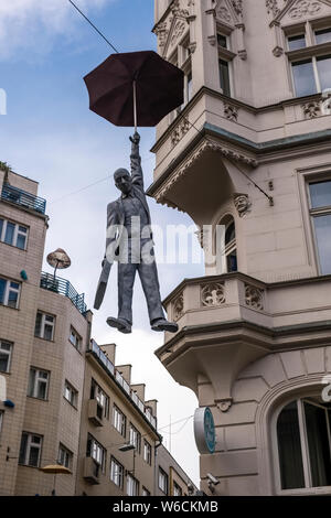 Streetart, die Skulptur von einem Mann mit einem Regenschirm in der Luft schweben zwischen Gebäuden Stockfoto