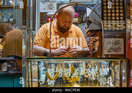 Türkische Juwelier und gold Kaufmann schafft eine Halskette in einem Souk im Zentrum von Istanbul, Türkei mit seiner Ware um ihn herum angezeigt. Stockfoto
