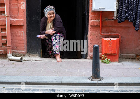 Eine ältere türkische Frau mit Kopftuch Umfragen die Aktivität auf der Straße vor ihrem Haus im Zentrum von Istanbul, Türkei Stockfoto