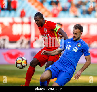 Nigerianischen Fußballspieler Odion Ighalo, Links, Changchun Yatai kickt den Ball einen Pass gegen die spanischen Fußballspieler Cala von Henan Jianye zu machen Stockfoto