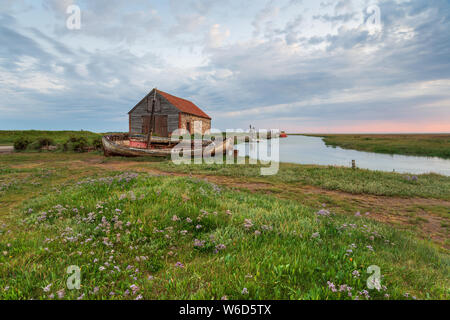 Sonnenaufgang über dem alten Hafen und Boote bei thornham an der nördlichen Küste von Norfolk Stockfoto