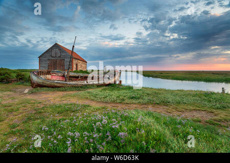 Sommer Sonnenaufgang über einem alten Kohle Scheune und Fischerboot an thornham an der nördlichen Küste von Norfolk Stockfoto