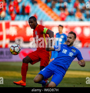 Nigerianischen Fußballspieler Odion Ighalo, Links, Changchun Yatai kickt den Ball einen Pass gegen die spanischen Fußballspieler Cala von Henan Jianye zu machen Stockfoto