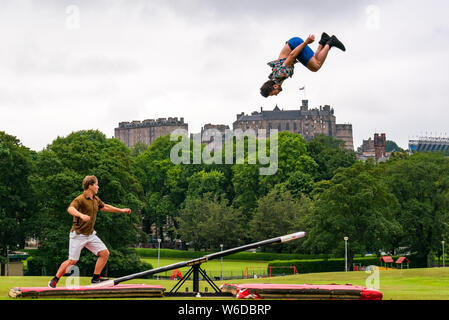 Edinburgh, Schottland, Vereinigtes Königreich, 1. August 2019. Edinburgh Festival Fringe: Die akrobatische Finnische aus Fringe zeigen Super Sonntag durch Race Horse Company mit einem teeterboard, sich in der Luft über die Wiesen mit den Edinburgh Skyline und das Edinburgh Schloss im Hintergrund zu starten. Bild: L bis R Akrobaten Rauli Dahlberg und Jarno Polhuijs Stockfoto