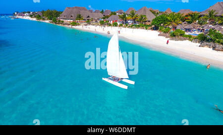 Weißes Segelboot im türkisblauen Meer mit klaren Wasser vor der Küste tropical beach White Sand Sansibar Stockfoto