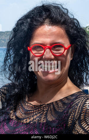 Attraktive Frau an einem Strand in Griechenland tragen helle rote Sonnenbrille Stockfoto