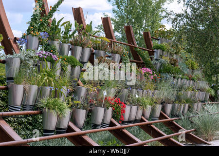 Verschiedene blühende Sommerblumen in Silber Töpfe auf einem Regal im Freien angeordnet Stockfoto