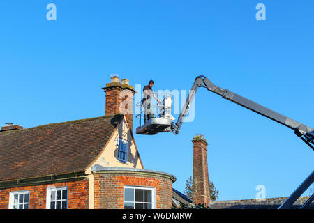 Arbeiter in einer hydraulischen Mann Hebebühne Warenkorb Kran außerhalb ein altes Haus in Hungerford, einer historischen Stadt in Berkshire, England Stockfoto