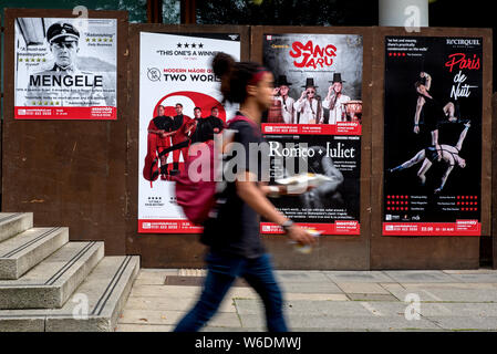 Eine junge Frau zu Fuß durch Werbeplakate für Edinburgh Fringe Festival zeigt. Edinburgh, Schottland, Großbritannien. (Mit Motion Blur) Stockfoto