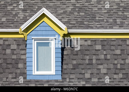 Blau und Gelb Fenster gegen graue Wand, typische Architektur der Magdalen Islands, Kanada. Minimalismus Stil mit Platz für Text. Stockfoto