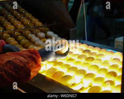 Ein Arbeitnehmer, der die Kontrollen der gesalzene Ente Eier unter den Lichtern bis das Doppelte - Eigelb Enteneier in Gaoyou Pick, Yangzhou Stadt, im Osten der Provinz Jiangsu, China Stockfoto