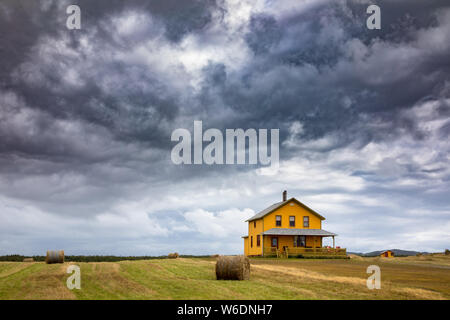 Gelbes Haus auf einer Klippe in Havre Aubert, Magdalen Islands. Dramatische sotmy Himmel und Heuballen im Vordergrund. Bild aus öffentlich Stellung genommen. Stockfoto