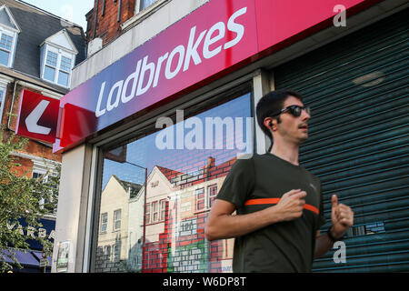 London, Großbritannien. 01 Aug, 2019. Ein Mann joggt Vergangenheit eine spielende Kommission Geldbußen, Ladbrokes Marke und Logo in London gesehen. Credit: SOPA Images Limited/Alamy leben Nachrichten Stockfoto