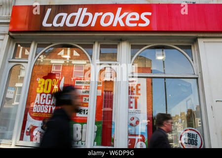 London, Großbritannien. 01 Aug, 2019. Menschen gehen vorbei an einem spielende Kommission Geldbußen, Ladbrokes Marke und Logo in London gesehen. Credit: SOPA Images Limited/Alamy leben Nachrichten Stockfoto