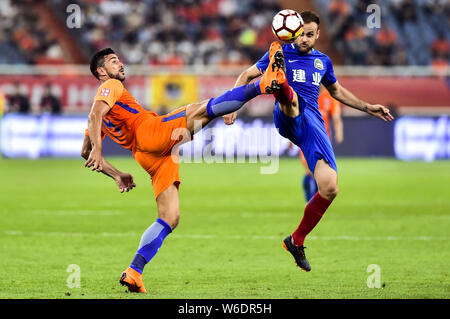 Italienische Fußballspieler Graziano Pelle, links, von Shandong Luneng Taishan Herausforderungen spanischer Fußballspieler Cala von Henan Jianye in der 8. Runde ma Stockfoto