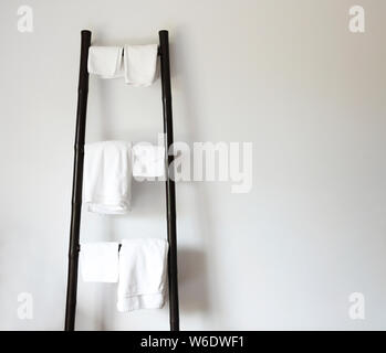 Weiße Handtücher hängen auf rustikalen Holzleiter. Wand Hintergrund mit Kopie Raum Stockfoto