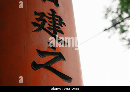 Alte japanische Kanji Inschriften auf ein hölzernes Tor mit dem Himmel im Hintergrund geschrieben. Die beiden Zeichen sind "Ken" und "Yuki". Stockfoto