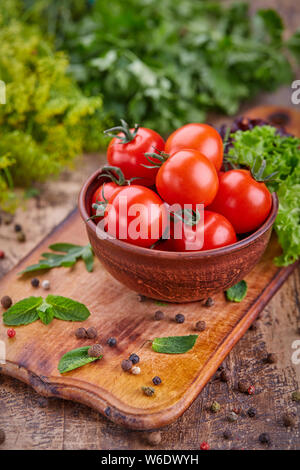 Teller mit Tomaten auf dem Hintergrund der Kräuter Stockfoto