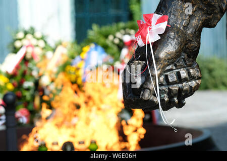 Warschau Polen - Donnerstag, 1. August - Detail auf der Warschauer Aufstand Denkmal in Warschau mit einem widerstandskämpfer Holding eine Handgranate mit Gedenkstätte Blumen und Flammen hinter Polen erinnert an den 75. Jahrestag des Warschauer Aufstands (Powstanie Warszawskie) gegen die Besatzungsmacht deutschen Armee am 1. August 1944 - Der Warschauer Aufstand Widerstandskämpfer der Heimatarmee (Armia Krajowa - AK) kämpfte auf für 63 Tage gegen die nationalsozialistische Kräfte als Kapitulation vor der anrückenden sowjetischen Armee über den nahe gelegenen Fluss Weichsel wartete. Foto Steven Mai/Alamy leben Nachrichten Stockfoto