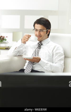 Geschäftsmann beim Fernsehen und bei einer Tasse Kaffee Stockfoto