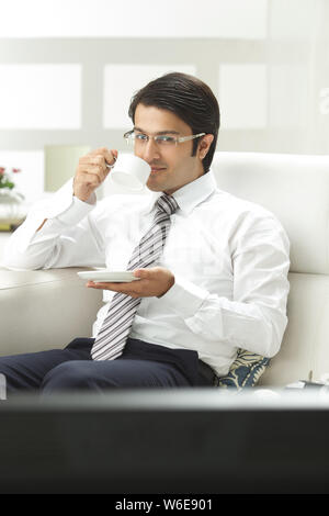 Geschäftsmann beim Fernsehen und bei einer Tasse Kaffee Stockfoto