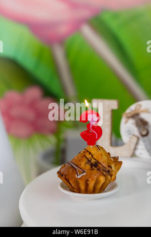 Geburtstag Kerze in Form der Zahl in Muffin. Nummer drei Geburtstag Kerze auf Cupcake auf einem weißen Tisch. Geburtstag Kuchen mit Schokolade Stockfoto