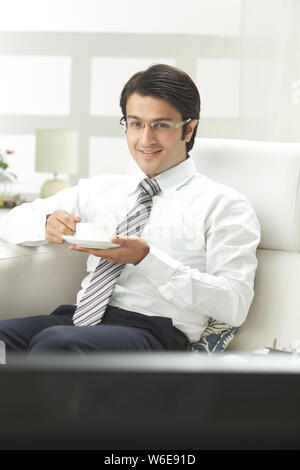 Geschäftsmann beim Fernsehen und bei einer Tasse Kaffee Stockfoto