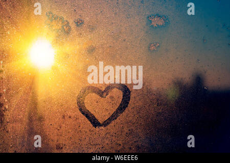 Atemberaubende vintage Orange sunrise Licht mit Herz Liebe Inschrift auf gefrorenen Fenster Glas. Soft Focus. Hintergrund mit kopieren. Stockfoto