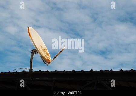 Gebrochen und alten Satellitenschüssel auf dem Dach und blauer Himmel. Stockfoto