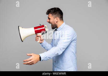 Seitenansicht der verärgerten Mann durch Megaphon vor weißem Hintergrund schreien Stockfoto