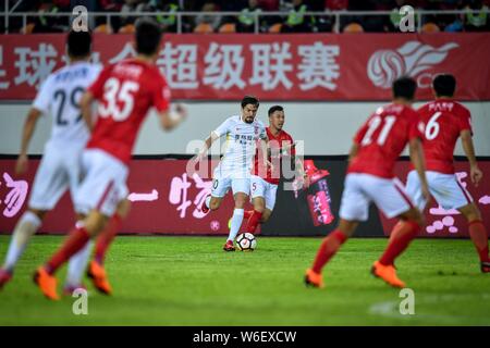 Dänischer Fußballspieler Lasse Vibe, Links, Changchun Yatai kickt den Ball einen Pass gegen einen Spieler von Guangzhou Evergrande Taobao in Ihrer sec zu machen Stockfoto