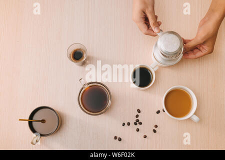 Tassen Kaffee mit Kaffeebohnen und vietnamesische Phin Filter auf Holz- Hintergrund Stockfoto