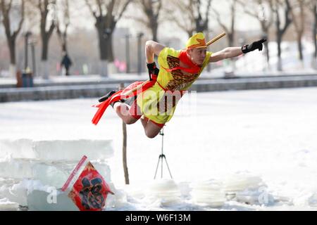Eine chinesische Winter schwimmen Enthusiasten in das Kostüm von Monkey King, einem wichtigen Charakter des Romans die Reise nach Westen gekleidet, führt lustig Tauchen Stockfoto