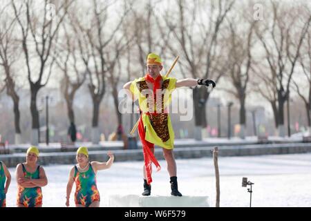 Eine chinesische Winter schwimmen Enthusiasten in das Kostüm von Monkey King, einem wichtigen Charakter des Romans die Reise nach Westen gekleidet, führt lustig Tauchen Stockfoto