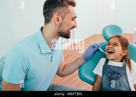 Hey Zeig mir deine Zähne. Männliche Zahnarzt Zähne überprüfen, ein kleines Mädchen in der zahnmedizinischen Klinik Stockfoto