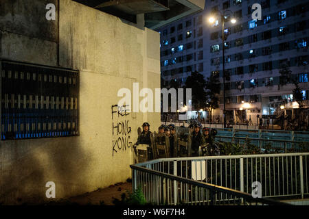 Der Polizei in Kampfausrüstung, neben dem ein Schild mit der Aufschrift "Freie Hongkong" bewegen, um es zu löschen Demonstranten bei Anti-Auslieferung bill Demonstrationen in Sha Tin, Hongkong, am 14. Juli 2019. Pro-demokratischen Demonstranten weiter mit Demonstrationen, wie sie für den vollständigen Abzug der eine umstrittene Auslieferung Bill und der Verwaltungschefin von Hong Kong Executive Carrie Lam. Stockfoto