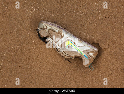 Single Trainingsschuh mit Nike Branding auf einem Strand bei Ebbe gefunden Stockfoto