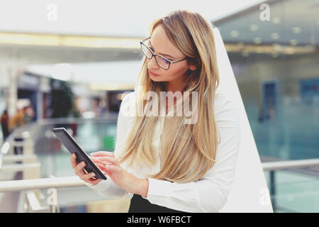 Blonde junge geschäftsfrau mit Tablette im Business Center Stockfoto