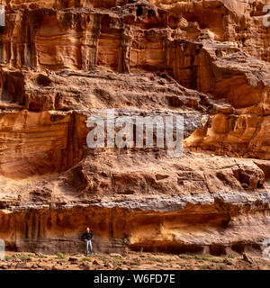 Eine junge Frau wird von riesigen Felsen im Wadi Rum, Jordanien in den Schatten gestellt. Stockfoto