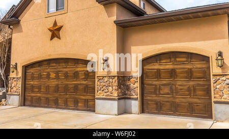 Panorama Fassade des schönes Haus mit zwei braunen Holz Garagentore gegen bewölkter Himmel Stockfoto