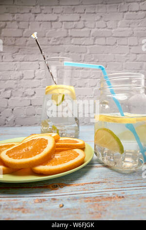 Blick auf ein Krug mit Limonade mit Eis und Zitrone neben einem grünen Platine mit Orangenscheiben Stockfoto