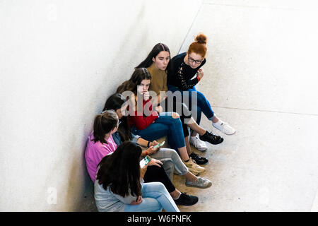 BERLIN, DEUTSCHLAND - 26. SEPTEMBER 2018: in, nach unten Perspektive einer Gruppe von Mädchen, die auf ihren Smartphones während einer Steinbank sitzend Gezoomt Stockfoto