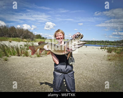 Die happy Fischerin hält in der Hand einen riesigen Hecht von 10 kg. Trophy fangen. Gute Angelmöglichkeiten. Stockfoto